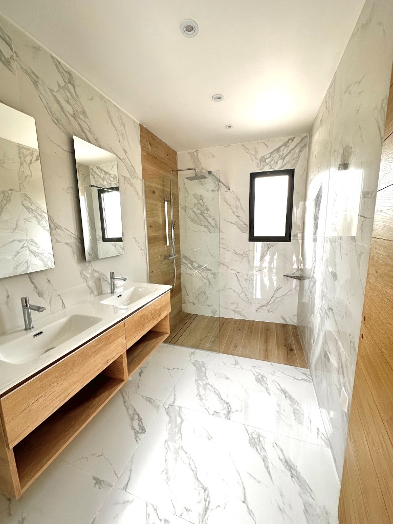 Salle de bain contemporaine mêlant carrelage marbre blanc et touches de bois